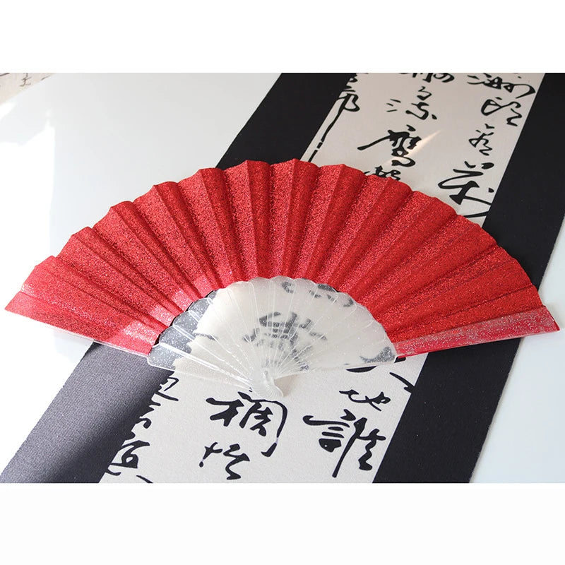 A red glitter folding fan with transparent ribs is displayed against a black background with Japanese text.