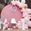 A pink balloon arch decoration featuring white and gold balloons for a first birthday party backdrop.