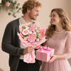 A young couple smiling while a man holds a pink bouquet of handcrafted crochet tulip flowers for a woman.