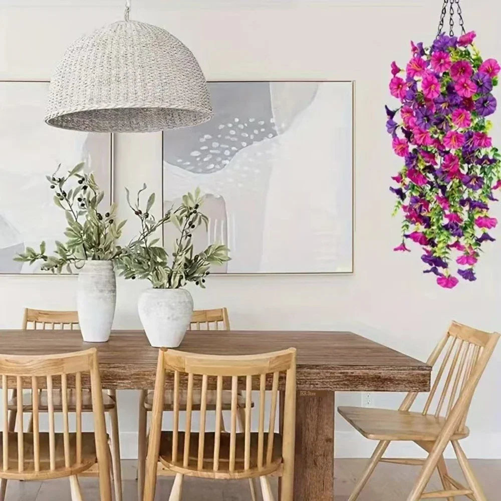 A vibrant purple morning glory and eucalyptus garland hangs on a wall above a wooden dining table.