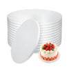 A stack of round white corrugated cake boards with a single decorated cake placed in front.