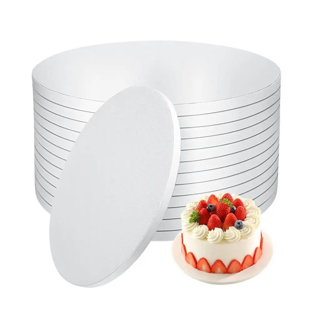 A stack of round white corrugated cake boards with a single decorated cake placed in front.