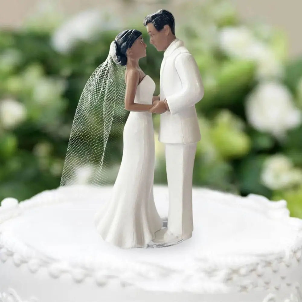 A wedding cake topper featuring an elegant bride and groom figurine embracing.