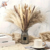 A dried flower bouquet of pampas grass in a silver vase resting on a beige linen fabric.