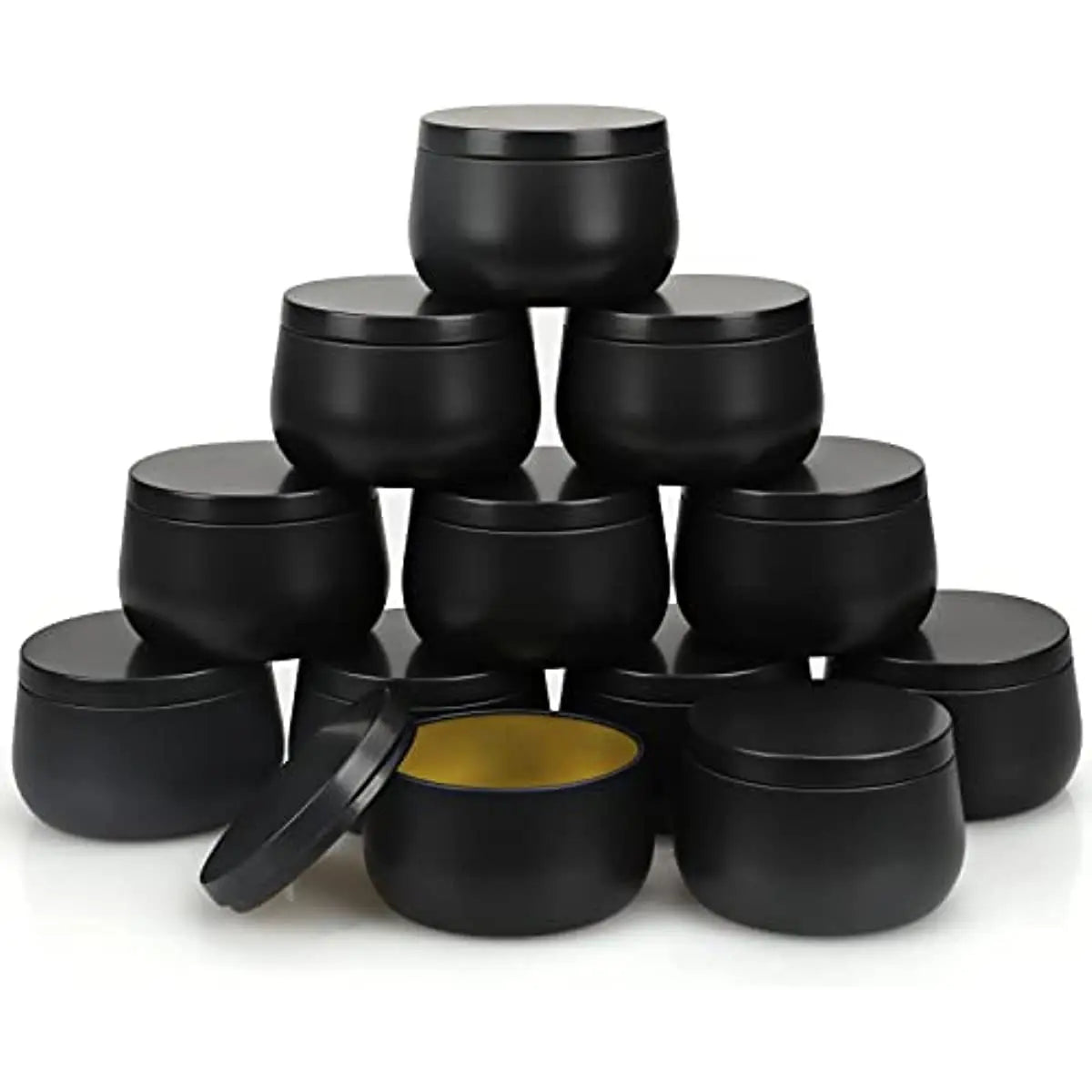 A stack of black metal candle tins with lids, including one open tin showing a gold interior.