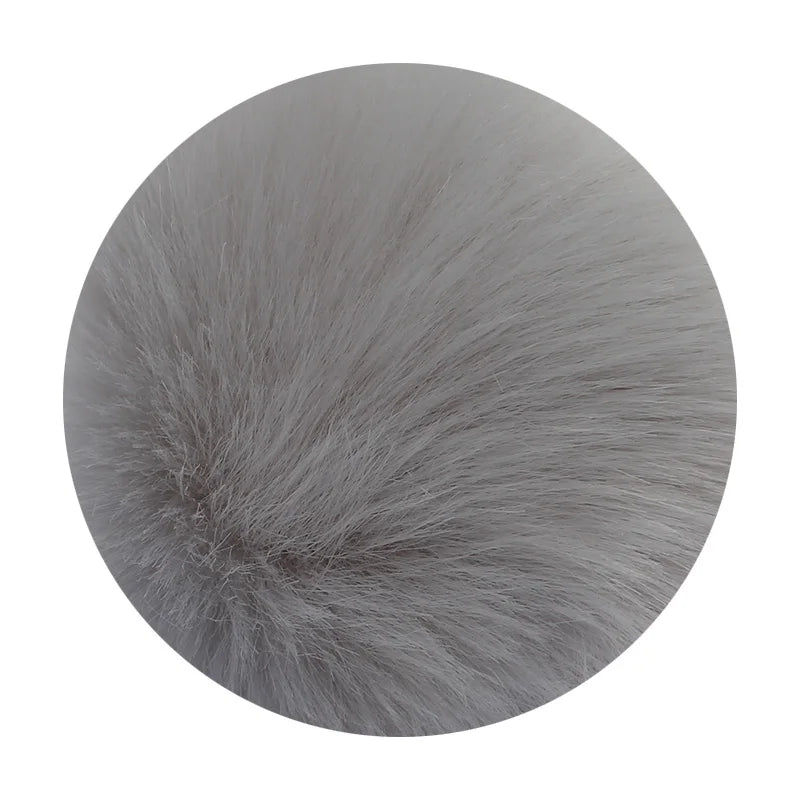 A round pom pom made of soft gray faux fur with a silver chain attached.