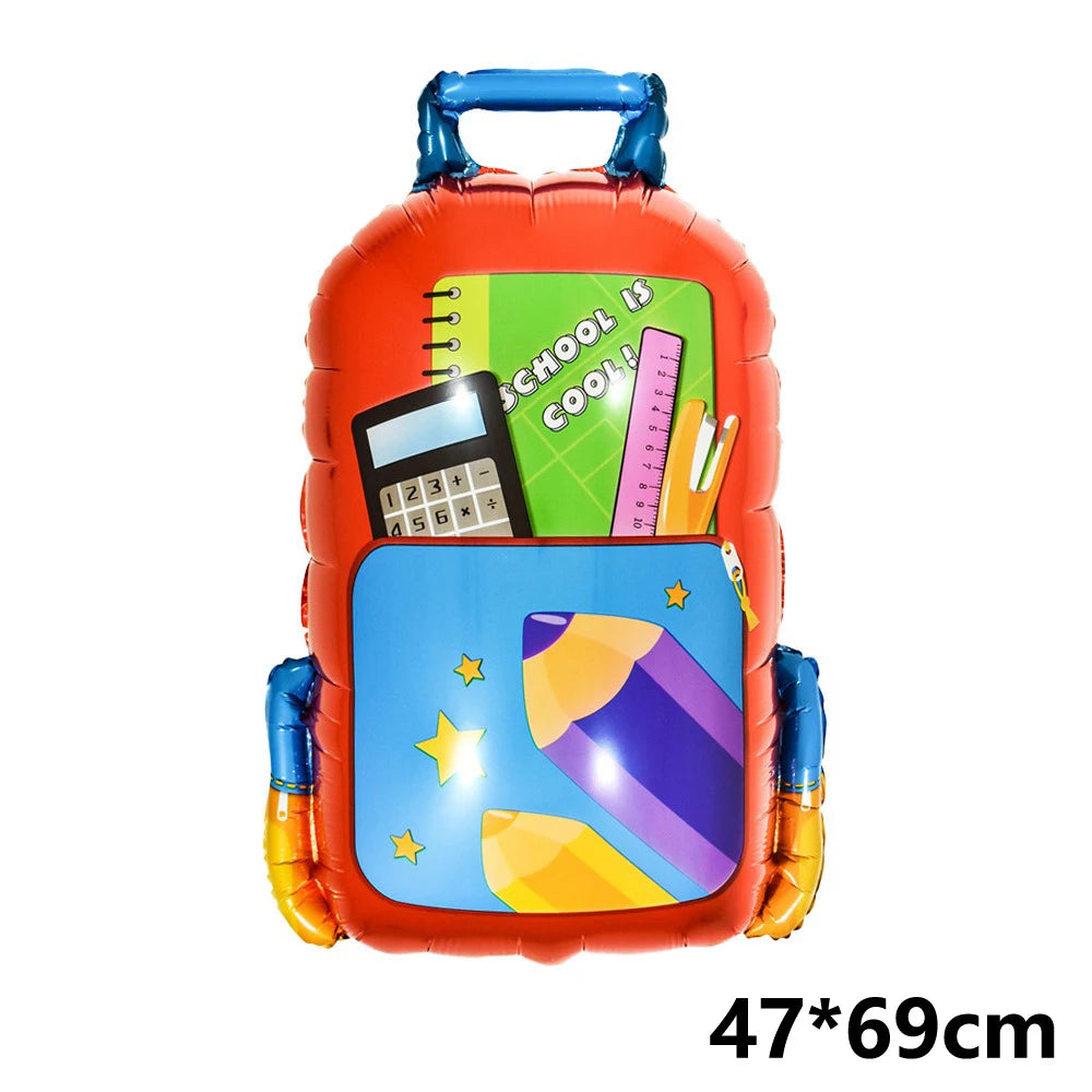 Orangees Folieballon in Form einer Schultasche mit bunten Schulmaterialien drinnen