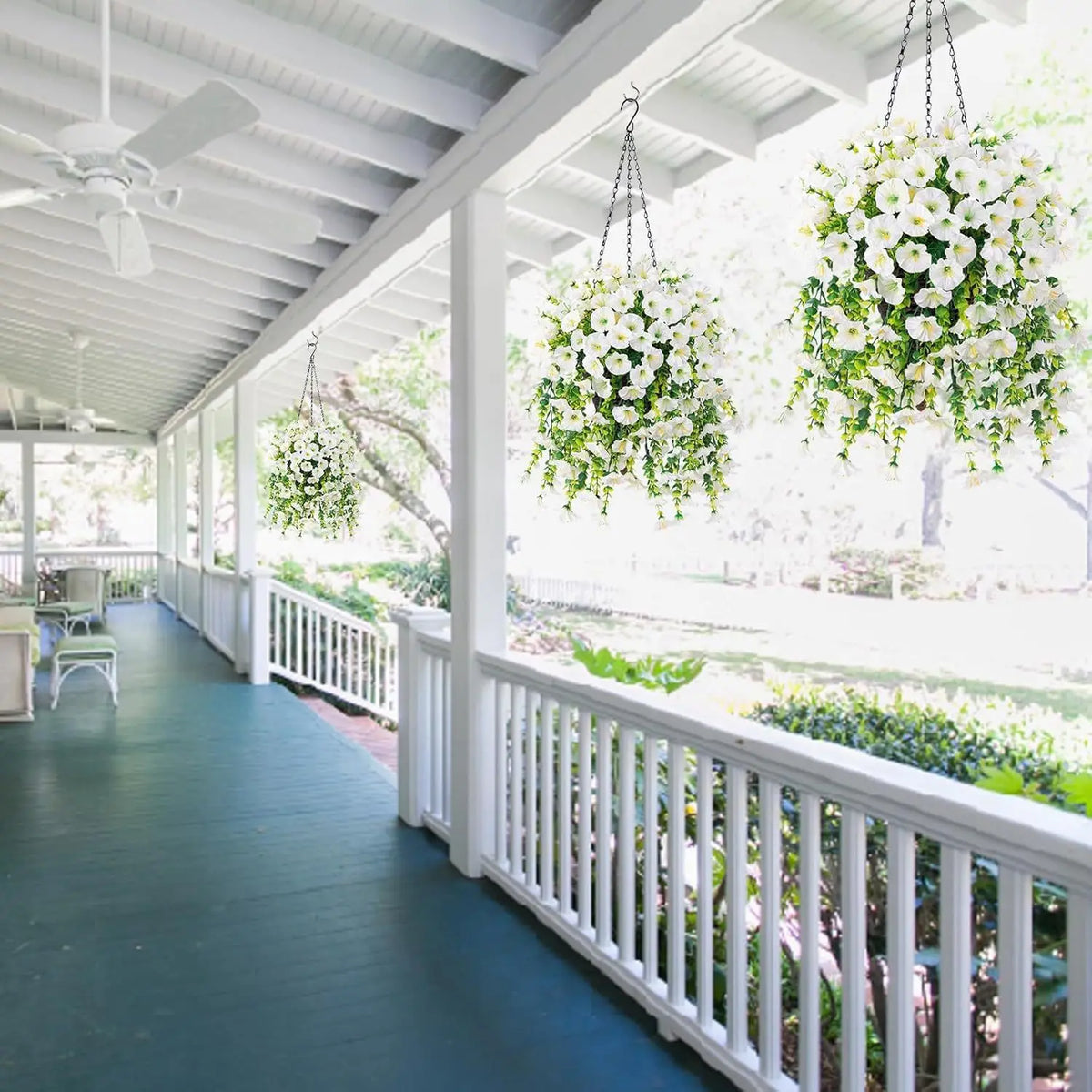Two hanging floral decor arrangements featuring white flowers and green eucalyptus on a porch walkway.