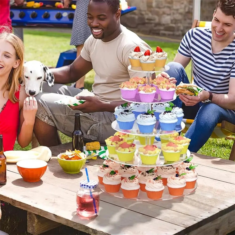 Mehrstöckiger Aussteller gefüllt mit bunten Cupcakes, auf einem Holztisch im Freien.