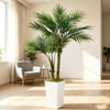 A tall artificial areca palm tree in a white planter stands in a bright, modern room.