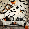 A white wall decorated with black bat silhouettes and a carved pumpkin, featuring a sofa and decorative elements.