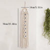 Cream macrame wall hanging with a long fringe and multiple blue evil eye pendants
