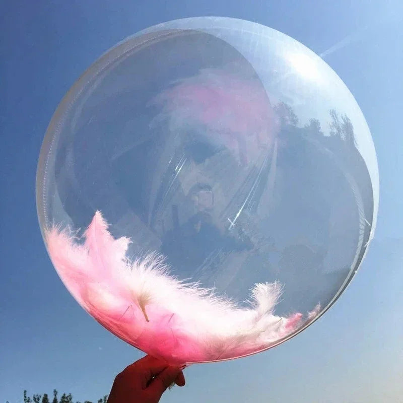 A clear bubble balloon filled with pink feathers against a blue sky.