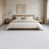 A minimalist bedroom featuring a wooden bed frame, light neutral bedding, and pale tiled floor.
