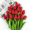 A bouquet of vibrant red artificial tulips with green leaves arranged for decoration.