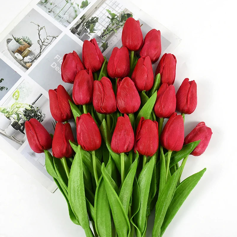A bouquet of vibrant red artificial tulips with green leaves arranged for decoration.