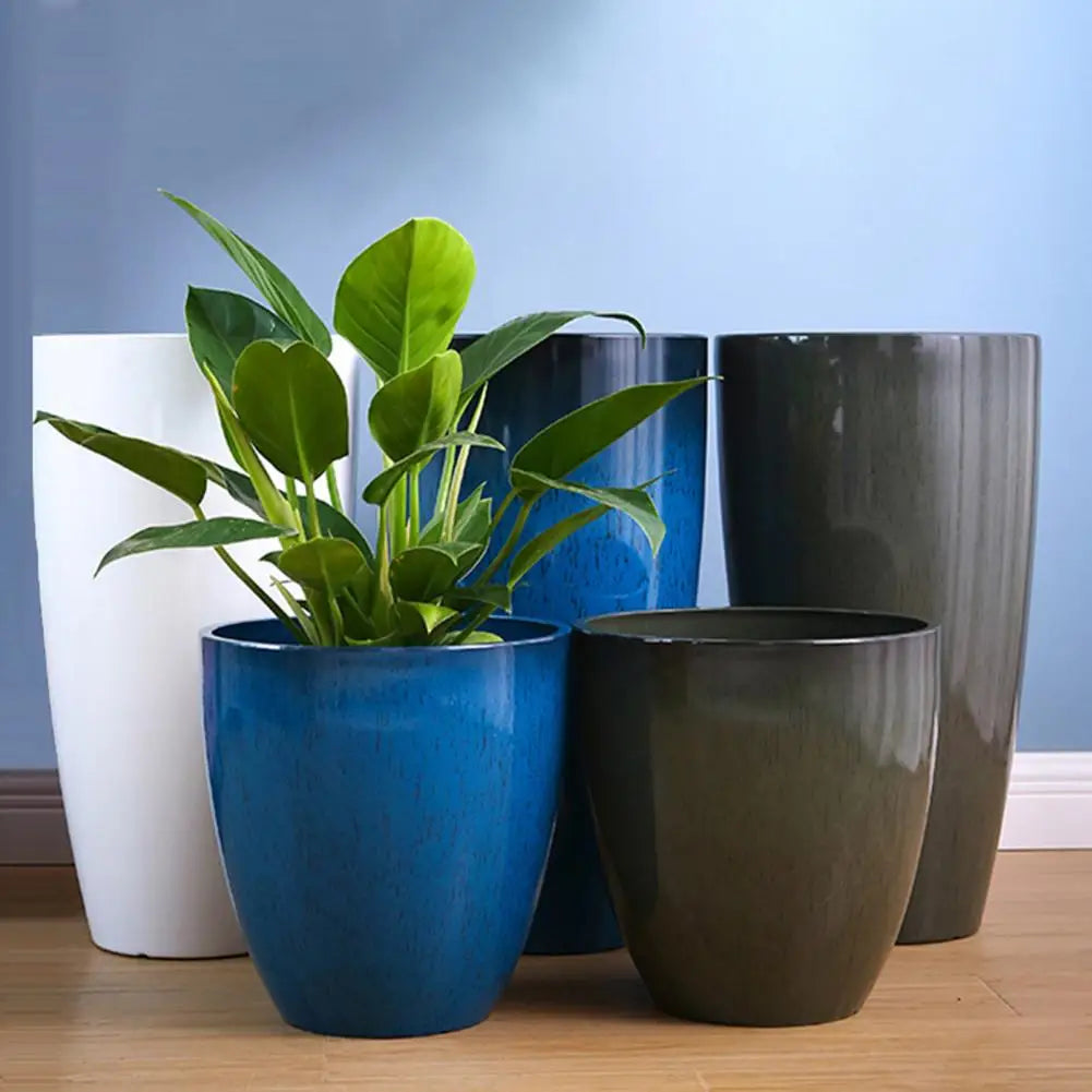 A collection of large, glossy blue and dark green resin planters for houseplants.
