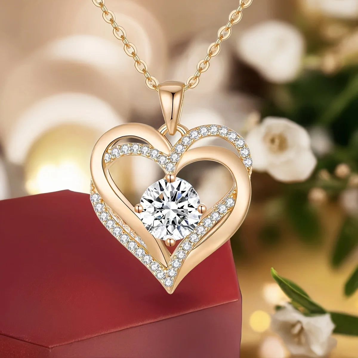 Gold heart pendant necklace featuring a clear diamond stone and surrounding pave diamonds, displayed on a red box.