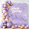 A purple and gold balloon arrangement against a shimmering purple sequin wall backdrop for a birthday party.