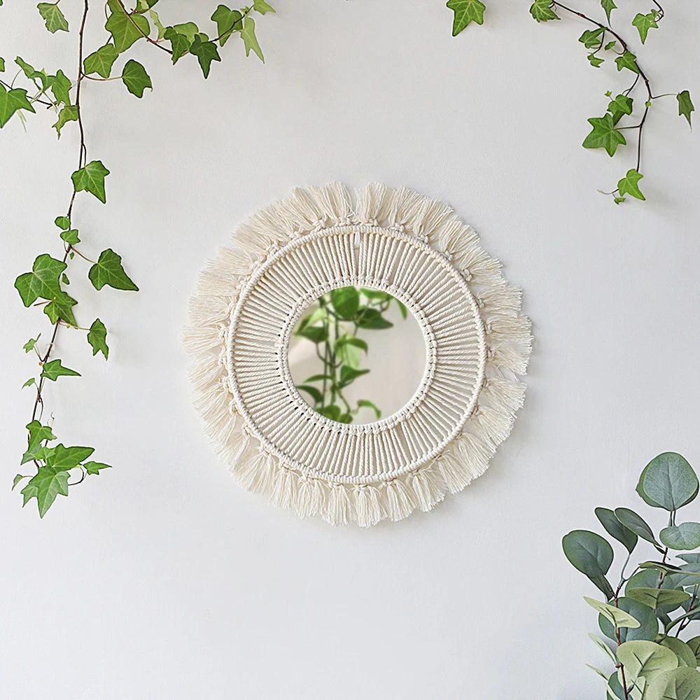 Miroir macramé rond avec frange beige naturelle, entouré de lierre vert.