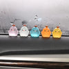 Five luminous resin chicken car ornaments in pink, white, blue, orange, and yellow sitting on a dark surface.