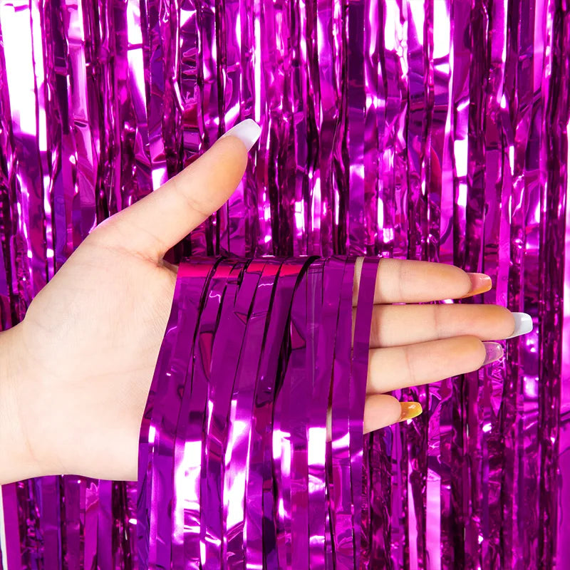 A hand holds purple metallic tinsel foil fringe curtain backdrop for parties.