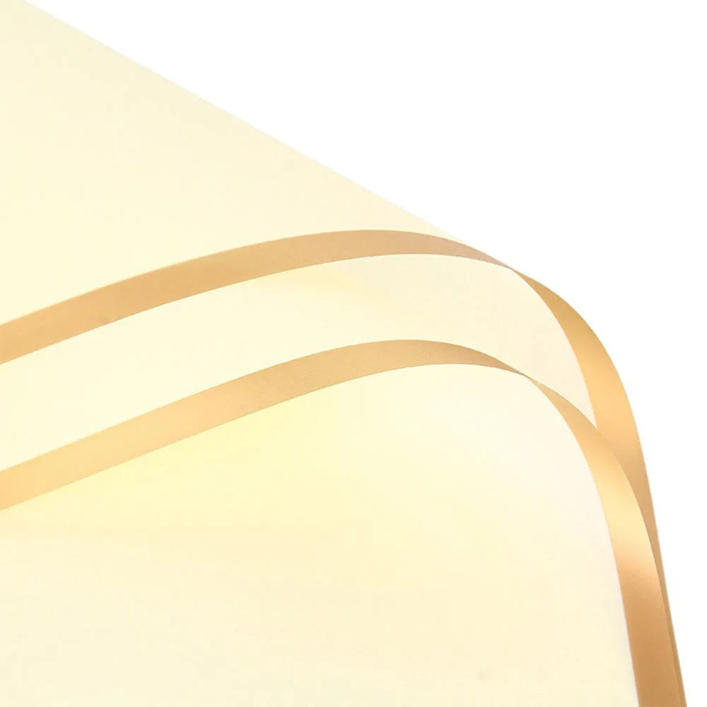 Close-up of a cream-colored wrapping paper with gold edges, showing a floral bouquet design.