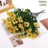 Yellow artificial daisy flower bundles in a green foliage arrangement
