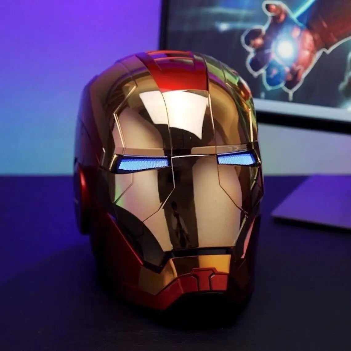 A metallic gold and red Iron Man helmet with blue LED eyes is displayed on a dark surface.