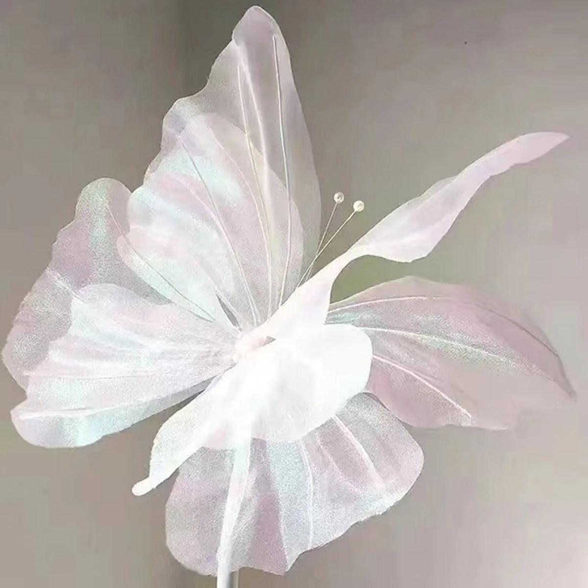 A delicate, translucent white and pink mesh butterfly decoration used as wall decor.