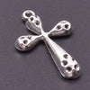 A silver cross charm with a textured surface and a loop, photographed against a dark gray background.