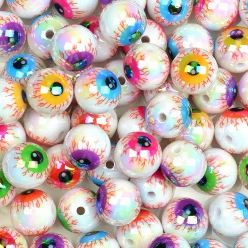 A collection of glossy, double-sided eyeball beads in various colors and iridescent finishes for crafting.