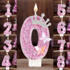 A large pink glitter candle shaped like the number 0 decorated with a crown and butterflies