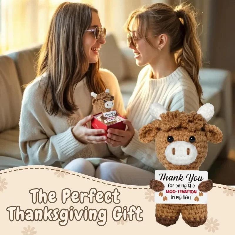 Two women smiling while holding a handcrafted crochet animal doll with a positive message card