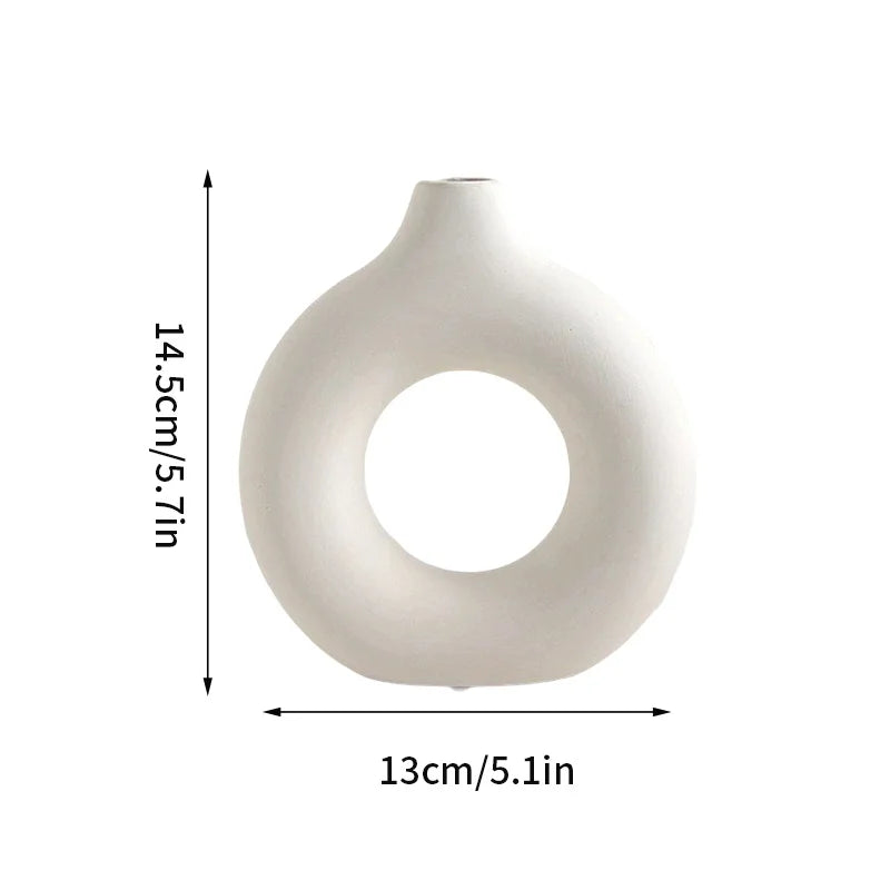 A white ceramic-style vase with a smooth, rounded body and an open circular mouth.
