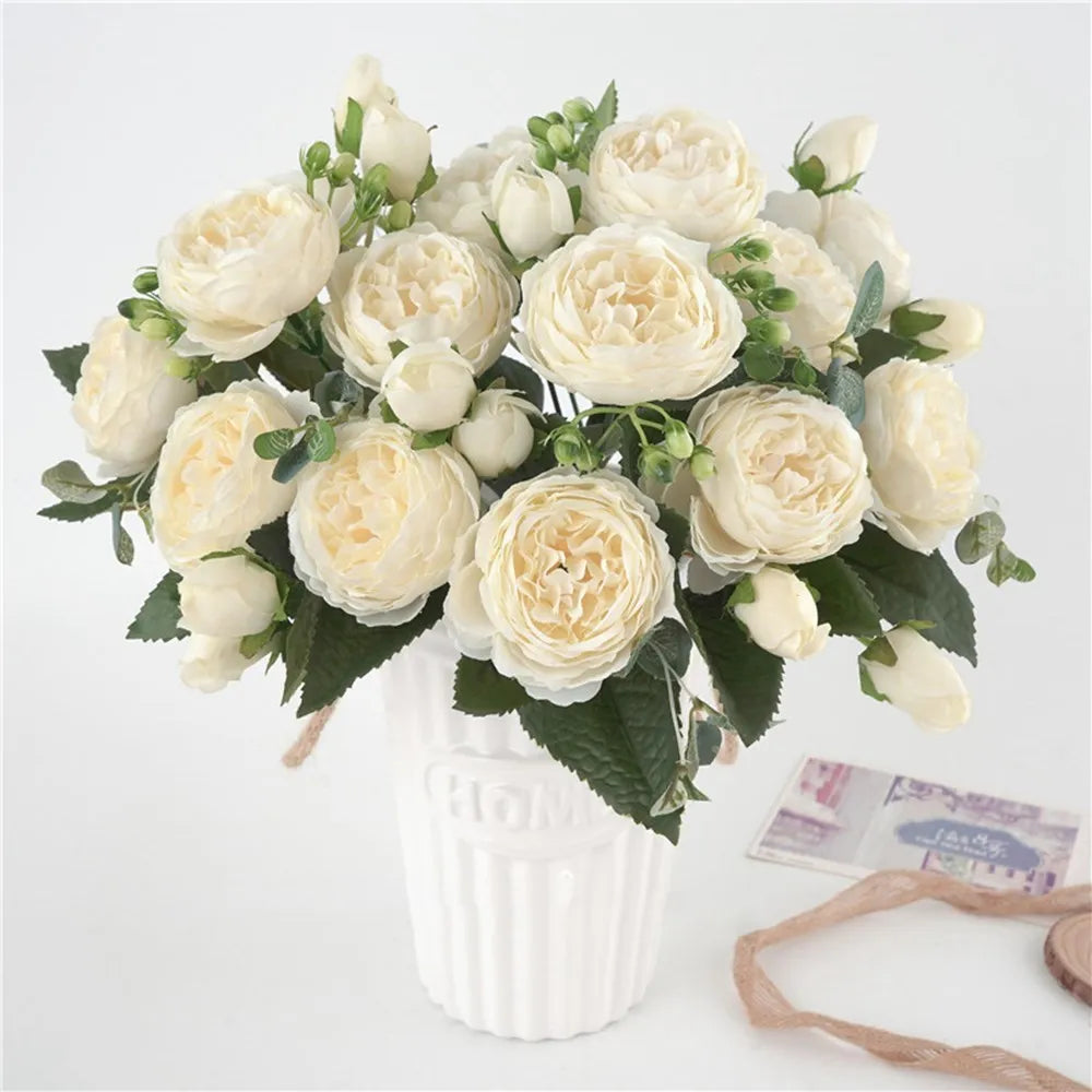 Ein Strauß künstlicher Seerosen und Pfingstrosen in Creme und Weiß in einer weißen Vase.