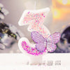 A white digital candle shaped like the number three decorated with pink and purple glitter, featuring a butterfly design.