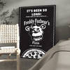A black framed poster featuring a cartoon Freddy Fazbear head and text inviting people to a pizza event.