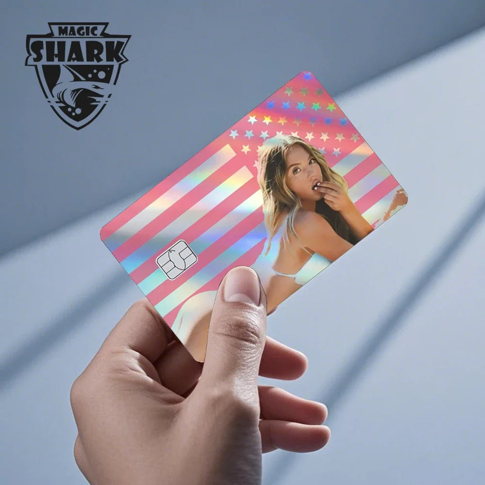 A hand holds up a holographic cat credit card skin sticker featuring a woman and patriotic stripes.