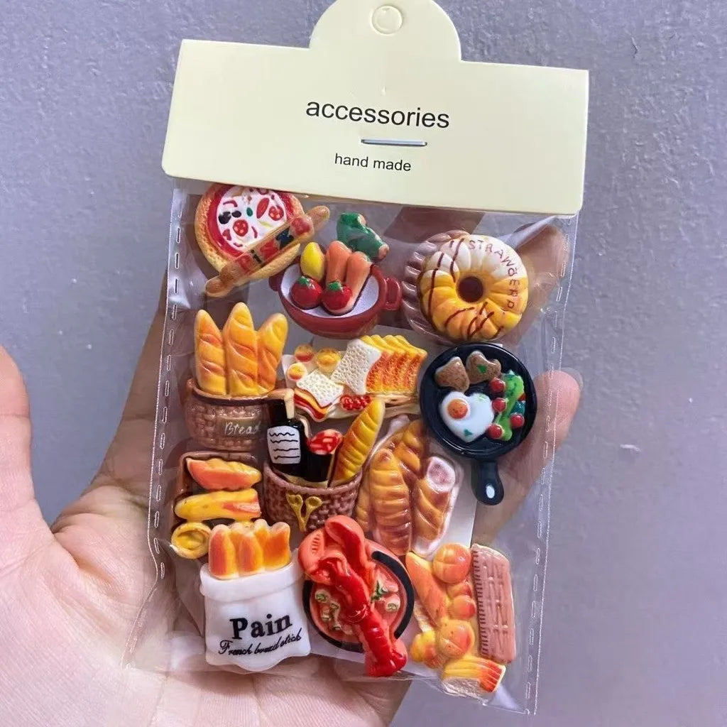 Un paquet en plastique transparent de aimants de réfrigérateur faits main avec des produits de boulangerie et des fruits.