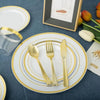 Service de table blanc avec bord doré, couverts et photo encadrée sur un tissu bleu foncé.