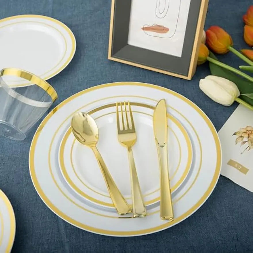 Service de table blanc avec bord doré, couverts et photo encadrée sur un tissu bleu foncé.