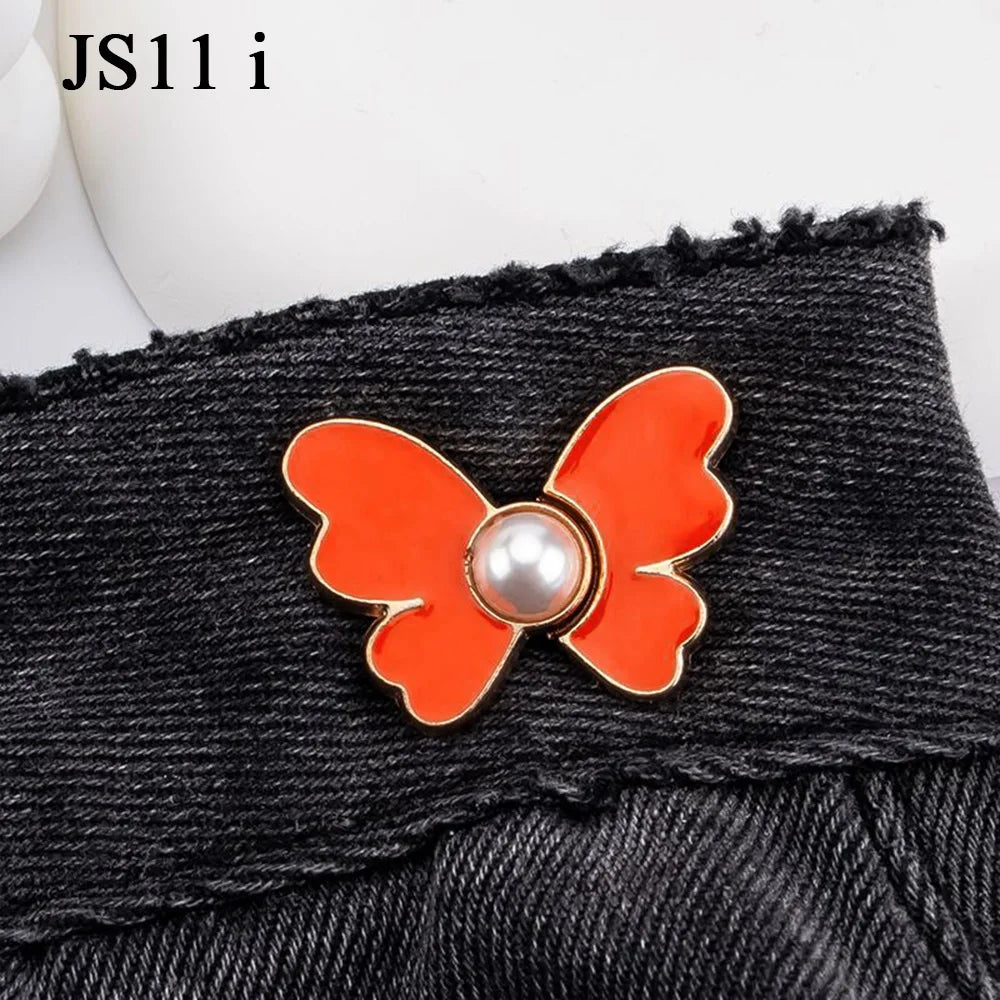 Orange and pearl butterfly buttons used as waist tightener closures on black denim jeans.