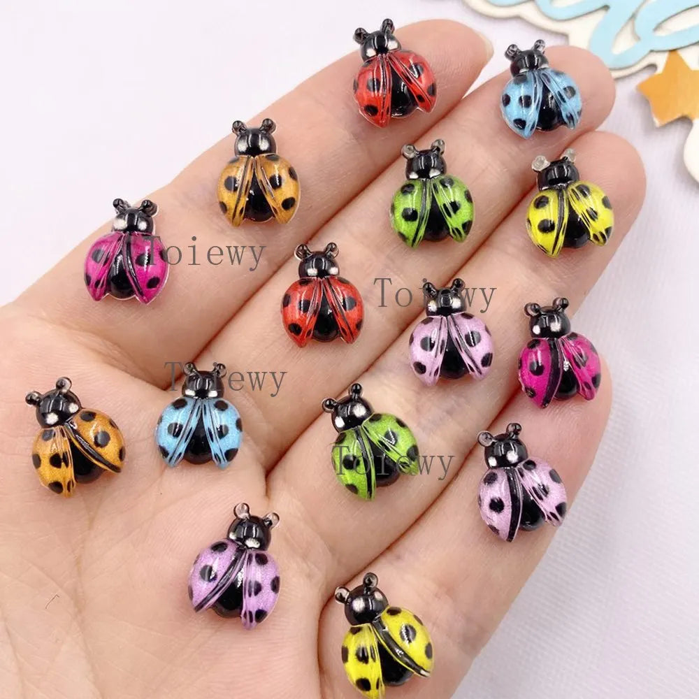 A collection of colorful resin beetle rhinestone appliques for DIY crafts displayed on a hand.