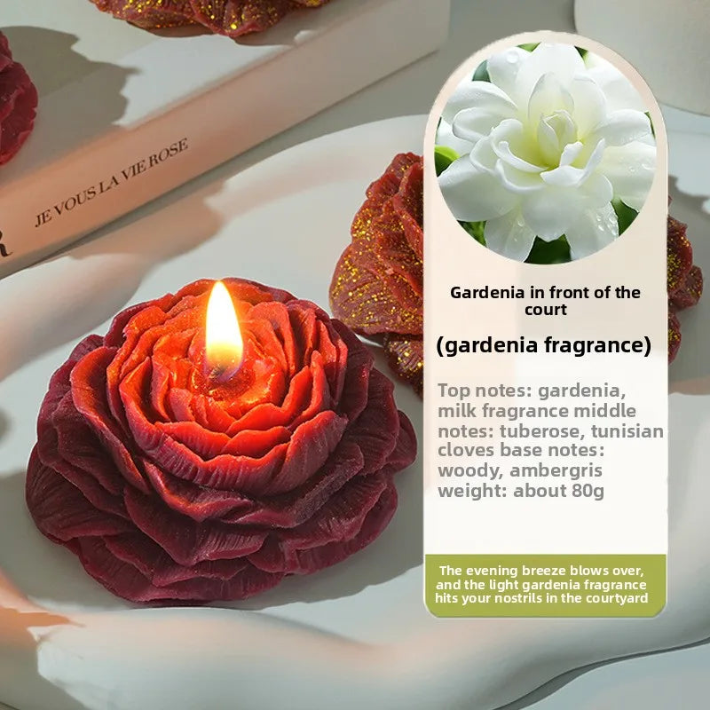 Dunkelrote Rosenkerze in Pfingstform, angezündet auf einem weißen Teller mit Beschreibung der Gardenien-Duftnoten.