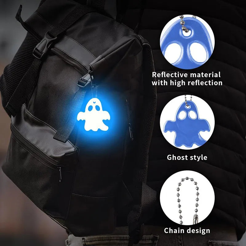 A black backpack features a ghost-shaped reflective keychain with a chain design.