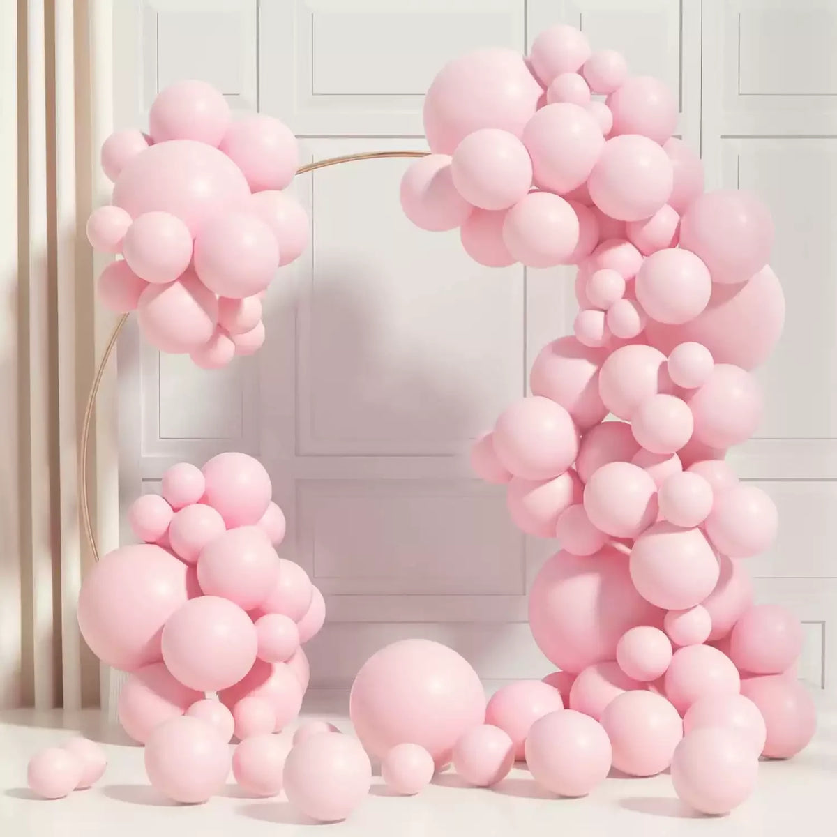 A cluster of pink balloons shaped like macarons in various shades arranged against a white background.
