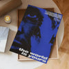 A dark blue and black poster titled The World Is Yours is displayed in a wooden frame on a light surface.
