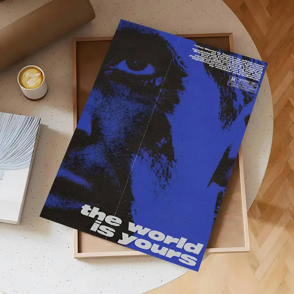 A dark blue and black poster titled The World Is Yours is displayed in a wooden frame on a light surface.