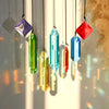 A collection of seven colorful crystal prism sun catchers hanging by thin strings against a bright background.